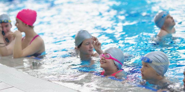 children at edge of pool, learning to swim in school swimming lesson