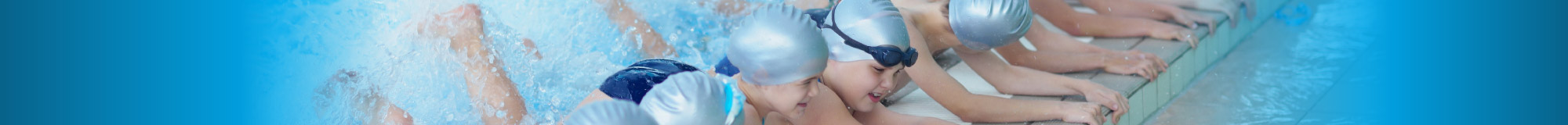 Children at school swimming lessons hanging on to wall whilst kicking in water